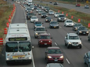 Bumper to bumper traffic on an interstate lined with orange cones.