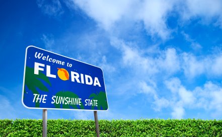 Sign in front of a big blue sky that reads "Welcome to Florida, The Sunshine State."