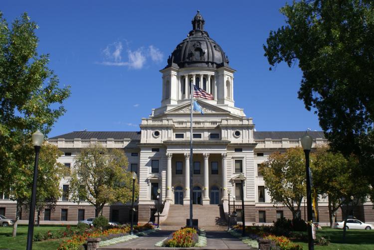 South Dakota state capitol; a large white building with a dome top and four pillars at the front of it.