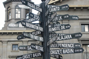 Street sign with a ton of different streets and directions; for example some say "Zoo" and "Pacific Ocean.