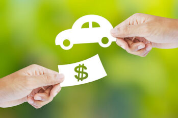 Two hands exchanging a dollar bill and a car, respectively, that symbolizes an auto insurance discount.