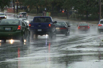 A number of cars all driving on a slick, slippery looking road.