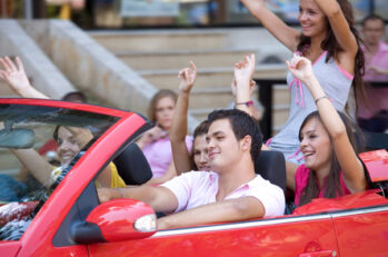 A red convertible full of teenagers looking like they're having a party in their car.