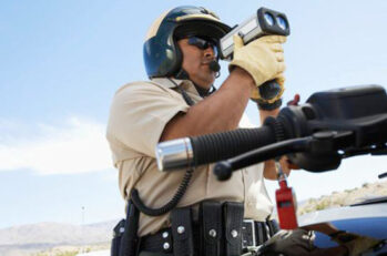 A motorcycle cop watching peoples speed with a radar device.