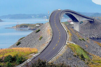 A road that turns into a bridge going over clear blue waters.