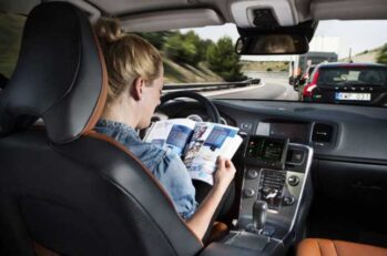 Woman reading a magazine while her self driving car drives itself.