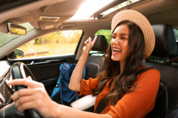 A happy woman drives down the road, ecstatic that she did the research, picked the best defensive driving course for her, and received her auto insurance discount.