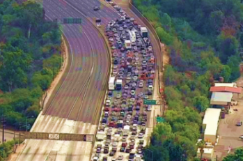 Am overhead shot of a backed up interstate with hundreds of cars on it.