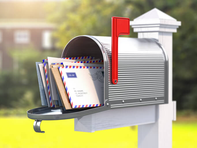 Open mailbox with letters on rural background.