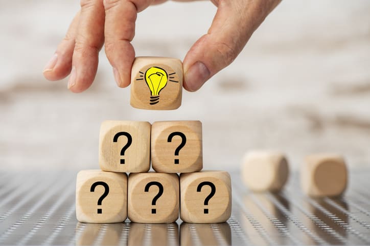 A set of blocks with question marks are topped with one with the image of a lit lightbulb.
